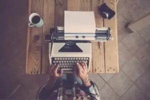 Top view of woman hands typing on typewriter keypad on paper. Woman typing on old typewriter