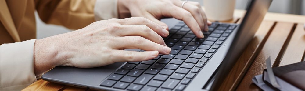 Hands of young businesswoman or solopreneur typing on laptop keyboard